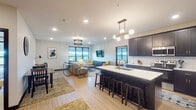 Located at 2620 Fairway Dr in Altoona, Wisconsin, this contemporary single-floor residence showcases a thoughtfully designed open-concept layout that seamlessly connects the kitchen, dining, and living areas. The kitchen is a standout feature, boasting dark espresso cabinetry that extends to the ceiling, pristine white quartz countertops, a classic subway tile backsplash, stainless steel appliances, and a large center island with bar seating — all illuminated by elegant globe pendant lighting. Light wood-tone flooring runs throughout the main living areas, adding warmth and continuity. The spacious living room is anchored by a striking chandelier, large windows offering outdoor views, a wall-mounted TV, and a tiled accent wall. Bedrooms offer a calm retreat with ceiling fans, plush carpeting, and generous windows that invite natural light and scenic views. The bathrooms maintain the home's cohesive dark cabinetry aesthetic with light flooring and clean, minimal finishes. Throughout the residence, dark interior doors and hardware provide sharp contrast against the neutral walls, creating a polished, modern aesthetic. The overall ambiance is one of contemporary elegance, balancing bold design choices with a welcoming, livable feel.