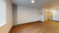 Located at 201 NE 103rd St in Seattle, WA, this single-floor, 3-bedroom, 2-bathroom residence offers a well-organized and functional layout. The open-plan kitchen and living area serves as the heart of the home, featuring warm wood-tone laminate flooring that extends throughout the unit. The kitchen is outfitted with light maple cabinetry, white appliances including a range, dishwasher, and refrigerator, recessed lighting, and ample counter space, making it both practical and inviting.

The three bedrooms are generously proportioned, each featuring the same wood-tone flooring, neutral painted walls, and windows with vertical blinds that allow natural light to fill the rooms. The primary bedroom includes a ceiling fan and a view of the surrounding neighborhood. Several bedrooms benefit from dedicated closet space, with multiple closets found throughout the unit.

The two bathrooms maintain a clean, modern aesthetic with light maple vanity cabinetry, white countertops, large mirrors, and neutral tile flooring. Natural wood-toned doors with warm-toned trim add a cohesive design element across the unit. A hallway connects the living spaces to the bedrooms and bathrooms, enhancing the overall flow of the floor plan. This residence offers a straightforward, comfortable living environment in the Northgate neighborhood of Seattle.