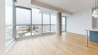 Located at 929 Richmond Rd in Ottawa's vibrant west end, this well-appointed one-bedroom, two-bathroom unit offers a thoughtfully designed open-concept layout finished with light hardwood flooring and crisp white walls throughout. The combined kitchen and living area forms the heart of the unit, where a sleek, modern kitchen showcases grey flat-panel cabinetry with gold hardware, a herringbone tile backsplash, stainless steel appliances, and a central island with an integrated breakfast bar — all illuminated by stylish pendant lighting. The expansive living room is defined by dramatic floor-to-ceiling windows that wrap the space, framing sweeping panoramic views of the Ottawa skyline and surrounding neighbourhood while flooding the interior with abundant natural light. A distinctive exposed concrete column adds an architectural accent to the living area. The bedroom is a comfortable, private retreat, also benefiting from large windows with outdoor views. Two well-appointed bathrooms feature clean, contemporary finishes, including white subway tile, hexagonal mosaic floor tile, chrome fixtures, a soaker tub, and a separate glass-enclosed walk-in shower. A dedicated closet and hallway complete the functional layout of this bright, modern urban residence.