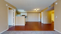 This single-floor unit offers a practical and comfortable layout with a seamless flow between its main living areas. Rich hardwood-style flooring runs throughout the entryway, kitchen, and living spaces, creating a warm and cohesive aesthetic. The open-concept living and dining area is generously proportioned, with warm yellow-toned walls and a textured ceiling that add character throughout. Large windows and a sliding glass door flood the space with natural light while providing views of surrounding greenery and access to a private balcony. The kitchen is efficiently designed with white cabinetry, a tile backsplash, a full suite of appliances including a gas range, refrigerator, and built-in microwave, and a peninsula that separates the kitchen from the living area. Carpet transitions into the bedroom areas, offering a softer underfoot experience. The bedrooms are well-sized, each featuring closet storage and easy access to a full bathroom. Two full bathrooms are present, each equipped with a single vanity, toilet, and a shower-tub combination. A louvered closet near the entry provides additional storage. The unit's layout is compact yet thoughtfully organized, making efficient use of every area throughout the single floor.