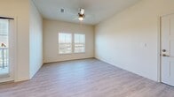 Located at 11901 Dionda Lane in Del Valle, TX, this one-bedroom, one-bathroom unit offers a thoughtfully designed single-level layout. The open-concept living and kitchen area forms the heart of the space, bathed in natural light from multiple windows fitted with blinds. Light wood-style luxury vinyl flooring runs throughout the main living areas, complemented by neutral, warm-toned walls and ceiling fans with light fixtures.

The kitchen is well-appointed with rich dark-brown shaker-style cabinetry, granite countertops, stainless steel appliances including a refrigerator, microwave, and range, and a peninsula that provides additional prep and seating space. The living area offers direct access to an exterior door, enhancing connectivity to the outdoors.

The bedroom is carpeted for comfort, features a ceiling fan, and connects to a dedicated walk-in closet with built-in shelving and hanging rods — offering generous storage. The bathroom continues the design language of the kitchen, with matching dark cabinetry, a granite vanity top, a large mirror, an overhead vanity light, and wood-style flooring. The overall ambiance is clean, modern, and move-in ready.