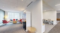 Located at 1717 N 12th St in Philadelphia, PA, this contemporary single-floor office space offers a well-appointed and thoughtfully designed work environment. The layout encompasses a large, open conference/training room anchored by bold circular pendant light fixtures and dressed with a striking patterned area rug in red, white, and gray tones. Bold red seating and light wood tables furnish the room, while floor-to-ceiling windows on multiple sides flood the space with natural light and frame panoramic views of the Philadelphia skyline and surrounding neighborhoods. Curated artwork adorns the walls, adding a creative dimension to the professional setting. Two private offices provide focused workspaces, each equipped with ergonomic seating, light wood desks with integrated power access, and individual task lighting. A welcoming lounge area features plush red accent chairs, a cushioned sofa, and a central coffee table set against a textured feature wall with globe pendant lighting, creating an inviting retreat for informal gatherings. Additional spaces include a quiet collaboration room with red and white task chairs and a small-group table with outdoor views, storage areas with modern built-in cabinetry, and a refreshment station. The design palette throughout is clean and modern, with neutral tones complemented by vibrant red accents.