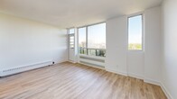 Located on the 10th floor at 70 Spadina Rd in Toronto's sought-after Annex neighbourhood, this efficiently laid-out unit offers a clean, modern aesthetic throughout. The space is finished with light-toned hardwood-style flooring that runs continuously, complementing the crisp white walls and creating a bright, airy atmosphere.

The two living areas are generously lit by large floor-to-ceiling windows that frame expansive views of the surrounding treetops, residential rooftops, and the Toronto skyline in the distance. A private balcony is accessible from the main living area, extending the sense of openness. Built-in baseboard heaters line the windows, and one of the living areas features a full-height mirrored sliding closet, adding both storage and a reflective depth to the room.

The bathroom is neatly appointed with classic white subway tile surrounding a soaking tub and shower combination, a compact vanity with a white finish, tile flooring, and chrome fixtures — delivering a clean and functional design.

Throughout the unit, the minimalist white palette, abundant natural light, and elevated treetop and city views combine to create a calm, comfortable living environment in one of Toronto's most vibrant and walkable neighbourhoods.