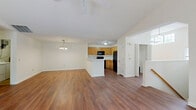 Located at 1063 Mosser Rd in Breinigsville, PA, this two-story, three-bedroom, two-bathroom home offers a well-organized and functional layout across its two levels. The main level is the heart of the home, featuring an open-concept design that seamlessly connects the living room, dining area, and kitchen. The kitchen is equipped with honey-toned cabinetry, black appliances including a refrigerator, microwave, and range, and a peninsula with a white countertop that provides additional prep space and a natural divide between the kitchen and living areas. Warm hardwood-style flooring runs throughout the main level, complemented by ceiling fans and a chandelier in the dining area. A utility room with in-unit washer and dryer hookups adds convenience. The attached garage features concrete flooring and bright windows admitting natural light. Upstairs, the generously sized primary bedroom impresses with soaring vaulted ceilings, hardwood-style floors, a ceiling fan, and transom windows. The en-suite primary bathroom includes a double-sink vanity with warm wood cabinetry, a large mirror, and a soaking tub. Two additional bedrooms and a second full bathroom complete the upper level, along with three closets for ample storage. A carpeted staircase with a wood handrail connects the floors.