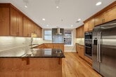 This 330 square foot studio apartment in Boston's India Street area masterfully combines contemporary design with historic elements. The single-floor layout maximizes space efficiency, featuring an open-concept living area flooded with natural light from large windows that offer street views. A standout feature is the exposed brick wall, adding warmth and character to the modern aesthetic.

The kitchen is a model of compact efficiency, boasting sleek white cabinetry, stainless steel appliances including a full-size refrigerator, oven, and built-in microwave. A small peninsula provides additional counter space and potential for casual dining.

The living area is versatile, with a raised platform that could serve as a sleeping or seating area. A wall-mounted TV enhances entertainment options without sacrificing floor space. Light wood flooring throughout unifies the space and adds to the bright, airy feel.

The bathroom, while compact, is thoughtfully designed with a modern vanity, ample storage, and a spacious walk-in shower featuring textured white tiles. Black fixtures provide a striking contrast to the overall white palette.

Climate control is ensured by a wall-mounted air conditioning unit. The apartment's layout, visible in the 3D model, demonstrates careful planning to maximize functionality in a limited footprint, making it an ideal urban dwelling for those seeking a blend of style and practicality in the heart of Boston.