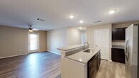 This single-floor residence offers a thoughtfully designed open-concept layout that seamlessly connects the kitchen, dining, and living areas. The kitchen is a standout feature, equipped with dark espresso cabinetry, granite countertops, a center island with a built-in sink, and a full suite of stainless steel appliances including a range, microwave, refrigerator with ice maker, and dishwasher. Recessed lighting illuminates the space, complementing the warm, neutral color palette found throughout.

The living area is generously proportioned, featuring hardwood-style flooring and a ceiling fan with a light fixture. Natural light filters in through a windowed exterior door, adding brightness to the open space. The same durable flooring extends throughout the residence, creating a cohesive and easy-to-maintain aesthetic.

The bedrooms are comfortable and well-sized, each featuring ceiling fans and closet access. The two full bathrooms are cleanly finished with tub-shower combinations, white subway tile surrounds, and light wood-tone flooring. Neutral wall tones and clean lines throughout the residence create a calm, move-in-ready atmosphere suitable for a variety of living arrangements.