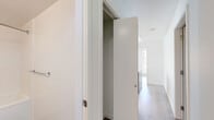 This well-designed 3-bedroom, 2-bathroom residence occupies a single floor and offers a bright, contemporary living experience with a thoughtful layout. The open, light-filled interior is defined by a clean white palette throughout, complemented by warm hardwood flooring that flows seamlessly from room to room.

The living area is a standout, featuring expansive floor-to-ceiling windows and sliding glass doors that frame sweeping urban skyline views, flooding the space with natural light. The bedrooms continue this theme, each offering generous windows — some with direct sliding door access — that deliver impressive city vistas and allow ample sunlight throughout the day. Closet storage is integrated into the bedroom areas, with sliding panel doors maintaining the unit's streamlined aesthetic. One bedroom features a more compact, efficient layout ideal for a home office or secondary use.

The hallway connects the rooms efficiently, with built-in storage closets accessible via sliding doors adding to the unit's practicality.

Both bathrooms are finished in a modern style with large-format tile flooring and warm wood-toned cabinetry. One bathroom features a soaker tub and shower combination, while the second offers a glass-enclosed walk-in shower. Both include white integrated vanities and chrome fixtures, maintaining a cohesive, refined look throughout.