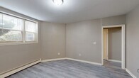 Located at 229-245 Parkside Ave in Buffalo, NY, this one-bedroom, one-bathroom unit offers a well-organized layout across a single floor, encompassing a living room, dining room, kitchen, bedroom, three closets, and two hallways. Throughout the unit, light-toned vinyl plank flooring and neutral warm-gray walls create a clean, cohesive aesthetic. Baseboard heating is present in multiple rooms, ensuring comfort year-round. The living and dining areas provide an open, functional space filled with natural light from several windows. The kitchen is thoughtfully appointed with white shaker-style cabinetry, dark granite countertops, a stainless steel sink, and a window overlooking the exterior. The bedroom is a comfortable, well-proportioned space featuring two windows that invite natural light and outdoor views of the surrounding neighborhood. The bathroom stands out with classic black-and-white mosaic tile flooring, marble-patterned wall tiles in the shower enclosure, and a window for natural ventilation. Three closets distributed throughout the unit provide ample storage. The overall ambiance is fresh and move-in ready, reflecting modern updates while maintaining a practical and inviting atmosphere.