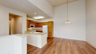 This two-story home offers a thoughtfully designed layout spread across two levels. The ground floor houses an attached garage with an automatic opener, providing secure, convenient parking and additional storage space with a concrete floor.

The main living level is bright and spacious, anchored by a combined kitchen and dining area that impresses with soaring vaulted ceilings and warm hardwood-style flooring. The kitchen features rich wood cabinetry, a full suite of white appliances including a refrigerator, range, built-in microwave, and dishwasher, along with a peninsula with a tile countertop and sink — ideal for casual dining or meal prep. A pendant chandelier adds an elegant touch to the adjacent dining space.

The living room enjoys an open, airy feel with generous natural light, while a hallway leads to the dedicated laundry area, which includes a full-size washer and dryer and upper cabinetry for storage.

Both bedrooms are carpeted and well-proportioned, with the primary bedroom offering ample space and access to a private bathroom featuring hardwood-style flooring and a walk-in closet. The second bedroom is bright with large windows that invite natural light. Multiple closets throughout provide abundant storage. A balcony extends the living space outdoors. Carpeted stairs with a white handrail connect the two levels seamlessly.