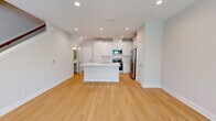 This two-story home in Jacksonville, FL offers a well-designed layout across two floors, with the main living areas on the ground floor and bedrooms above. The bright, open kitchen is a standout feature, equipped with white shaker cabinetry, a subway tile backsplash, stainless steel appliances including a refrigerator, range, and microwave, and a white quartz peninsula with an undermount sink — all complemented by light hardwood flooring. The living room continues the light and airy aesthetic with recessed lighting, a ceiling fan, large windows allowing natural light, and matching hardwood floors. Upstairs, three carpeted bedrooms each feature ceiling fans and windows with outdoor views. The spacious primary bedroom includes a generous walk-in closet outfitted with wire shelving. The three bathrooms are elegantly finished with marble-style tile on floors and walls, white cabinetry with brushed gold hardware, and quartz countertops; the primary bath features a double vanity and glass-enclosed shower. A dedicated laundry room houses a full-size washer and dryer. The attached garage offers ample space with a clean concrete floor and an automatic opener, completing this well-appointed Jacksonville home.