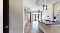 This 670 square foot apartment offers a thoughtful layout maximizing space and functionality. The single-floor design encompasses one bedroom, one bathroom, and an open concept kitchen and living area. The primary bedroom, measuring 170 square feet, provides ample space for rest and relaxation.

The interior is characterized by a contemporary aesthetic, featuring warm wood flooring throughout that adds a touch of natural elegance. Large windows with dark frames serve as striking architectural elements, allowing abundant natural light to flood the space and potentially offering views of the surrounding area.

The neutral color palette, dominated by light walls, creates a sense of openness and versatility. Dark accents, such as the window and door frames, provide a sophisticated contrast, enhancing the overall modern appeal of the apartment.

The visible doorway suggests well-proportioned rooms and smooth flow between spaces. While compact, the apartment appears to make efficient use of its square footage, likely incorporating smart storage solutions to maximize livability.

This space is ideal for those seeking a stylish, low-maintenance urban dwelling that balances comfort with contemporary design. Its streamlined layout and modern finishes make it well-suited for young professionals or small households desiring a chic city lifestyle.