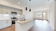This thoughtfully designed 3-bedroom, 3-bathroom home in Broomfield, Colorado offers a clean, contemporary aesthetic throughout. The open-concept kitchen and living area serves as the heart of the home, anchored by a large center island with a quartz countertop, undermount sink, and matte black pendant lighting overhead. Gray shaker-style cabinetry, a marble-look tile backsplash, and a full suite of stainless steel appliances — including a French door refrigerator, gas range, and built-in microwave — complete the well-appointed kitchen. Warm hardwood-style flooring flows seamlessly through the main living areas and bedrooms, complementing the bright white walls and abundant natural light from large windows. Each of the three bedrooms is generously proportioned, sun-filled, and includes dedicated closet space with built-in shelving and hanging rods. The primary bedroom features its own spacious walk-in closet. The bathrooms are finished with large-format gray tile flooring, white vanities, and framed mirrors. A dedicated laundry room with a full-size washer and dryer adds everyday convenience. Hallways connect the layout efficiently, making the home feel open yet functional throughout.