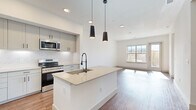 This thoughtfully designed 3-bedroom, 3-bathroom home in Broomfield, Colorado offers a clean, contemporary aesthetic throughout. The open-concept kitchen and living area serves as the heart of the home, anchored by a large center island with a quartz countertop, undermount sink, and matte black pendant lighting overhead. Gray shaker-style cabinetry, a marble-look tile backsplash, and a full suite of stainless steel appliances — including a French door refrigerator, gas range, and built-in microwave — complete the well-appointed kitchen. Warm hardwood-style flooring flows seamlessly through the main living areas and bedrooms, complementing the bright white walls and abundant natural light from large windows. Each of the three bedrooms is generously proportioned, sun-filled, and includes dedicated closet space with built-in shelving and hanging rods. The primary bedroom features its own spacious walk-in closet. The bathrooms are finished with large-format gray tile flooring, white vanities, and framed mirrors. A dedicated laundry room with a full-size washer and dryer adds everyday convenience. Hallways connect the layout efficiently, making the home feel open yet functional throughout.