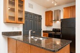 Located at 3217 Pleasant Garden Rd in Greensboro, NC, this single-floor home offers a well-organized layout with a variety of functional living spaces. The kitchen serves as a central highlight, featuring a peninsula island topped with rich dark granite countertops, an integrated stainless steel sink, warm wood cabinetry with glass-front upper cabinets, a stainless steel range hood, and black appliances including a gas range and refrigerator. Track lighting illuminates the space, which transitions seamlessly between hardwood-style flooring and plush carpeting in the adjoining areas. The bedrooms are generously sized, each finished with neutral carpet and ceiling fans for year-round comfort. One bedroom includes a walk-in closet and a window with outdoor views, while another opens via French doors to an exterior space, allowing natural light to fill the room. The bathrooms are cleanly appointed — one features warm wood cabinetry, a dark granite vanity top, hardwood-style flooring, and a tub-shower combination, while a second bathroom offers a white tub-shower surround with brushed nickel fixtures and wood cabinetry. Throughout, the home maintains a neutral, light-toned palette with white walls and clean finishes, creating a bright and livable atmosphere.