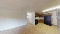 This single-floor unit offers a practical and straightforward layout designed for comfortable everyday living. The open-concept living area flows directly into the kitchen, creating a connected and functional common space. The living room is finished with neutral wall-to-wall carpeting and features a sliding glass door that opens to a private balcony, allowing natural light to fill the room and providing outdoor views of surrounding greenery.

The kitchen is positioned adjacent to the living area and is equipped with warm-toned wood cabinetry featuring decorative hardware, light countertops, a stainless steel sink, a black gas range with overhead ventilation, and a full-size black refrigerator. Tile flooring and a tiled backsplash complete the kitchen's functional aesthetic.

A hallway connects the living space to the private rooms, each carpeted and finished with neutral paint. The bedrooms each feature windows that bring in natural light and views of the surrounding neighborhood. Baseboard heating units run along the perimeter walls throughout the unit, providing consistent climate control. Textured ceilings are consistent throughout, contributing to the unit's understated, no-frills character.