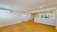 Located at 200 Broadway in Troy, NY, this well-appointed one-bedroom, one-bathroom unit offers a thoughtfully designed single-floor layout with a generous overall footprint. The open-concept living and kitchen area serves as the heart of the home, featuring warm light hardwood flooring, recessed lighting, and track lighting that brightens the space. A wall-mounted mini-split system ensures year-round climate comfort. Built-in shelving adds functional character to the living area, which flows seamlessly toward a large kitchen peninsula. The kitchen is outfitted with white shaker-style cabinetry, a crisp white countertop, stainless steel appliances including a refrigerator and range, and elegant pendant lighting above the island. Open shelving provides additional storage and display space. The spacious bedroom is finished with plush wall-to-wall carpeting, a double closet, and a wall-mounted mini-split unit, offering a quiet and comfortable retreat. Natural light filters in through multiple windows fitted with classic white blinds. The bathroom features neutral tile flooring, a vanity with a white countertop, a large mirror with overhead lighting, and clean, simple finishes that complete the polished look of this well-maintained unit.