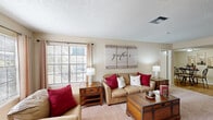 This single-floor home in Kenner, Louisiana offers a well-organized layout across three bedrooms and two full bathrooms. The living room serves as the heart of the home, featuring a classic fireplace with a white mantel, a large mirror accent, and French doors that invite natural light. Large windows with blinds and curtain panels brighten the carpeted space, creating a warm and welcoming atmosphere.

Adjacent to the living room, the dining area transitions seamlessly via wood-look flooring, offering a defined space for everyday meals. The galley-style kitchen runs along one wall with light wood cabinetry, stone-look countertops, a stainless steel sink, and a full suite of appliances including a dishwasher and refrigerator. A pass-through counter connects the kitchen to the dining area, enhancing the open feel.

The primary bedroom is a comfortable retreat featuring dual closets, a ceiling fan with light, and plush carpeting. The additional bedrooms are similarly appointed with ceiling fans and closet access. Both bathrooms feature wood-look tile flooring, vanities with stone-look countertops, and tub-shower combinations. A hallway connects all rooms, contributing to the home's efficient and functional single-floor design.