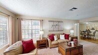 This single-floor home in Kenner, Louisiana offers a well-organized layout across three bedrooms and two full bathrooms. The living room serves as the heart of the home, featuring a classic fireplace with a white mantel, a large mirror accent, and French doors that invite natural light. Large windows with blinds and curtain panels brighten the carpeted space, creating a warm and welcoming atmosphere.

Adjacent to the living room, the dining area transitions seamlessly via wood-look flooring, offering a defined space for everyday meals. The galley-style kitchen runs along one wall with light wood cabinetry, stone-look countertops, a stainless steel sink, and a full suite of appliances including a dishwasher and refrigerator. A pass-through counter connects the kitchen to the dining area, enhancing the open feel.

The primary bedroom is a comfortable retreat featuring dual closets, a ceiling fan with light, and plush carpeting. The additional bedrooms are similarly appointed with ceiling fans and closet access. Both bathrooms feature wood-look tile flooring, vanities with stone-look countertops, and tub-shower combinations. A hallway connects all rooms, contributing to the home's efficient and functional single-floor design.