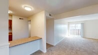 This single-floor residence offers a practical and comfortable layout designed for everyday living. The kitchen is equipped with warm-toned wooden cabinetry, granite-style countertops, a white electric range, built-in microwave, and a double sink, all set over durable hardwood-style flooring. A breakfast bar with a granite-style surface opens the kitchen toward the main living area, creating an easy flow between cooking and entertaining spaces.

The living and dining areas are generously proportioned, featuring neutral-toned carpet throughout and clean white walls that lend a bright, airy feel. A sliding glass door leads to a private balcony, allowing natural light to fill the space and providing a pleasant outdoor retreat.

A carpeted hallway connects the living areas to the private bedrooms, each of which features plush carpet flooring, windows that invite natural light, and ample wall space. The bathroom includes a wide vanity with a white countertop, integrated sink, and shaker-style cabinetry with brushed nickel hardware, complemented by a large mirror above.

Throughout the residence, the design maintains a consistent, neutral palette with practical finishes, creating a cohesive and move-in ready environment suited to a variety of lifestyles.