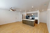 Located at 1415 Whitewater Dr in Idaho Falls, Idaho, this single-floor, one-bedroom, one-bathroom unit offers a thoughtfully designed layout with modern finishes throughout. The open-concept kitchen and living area serves as the heart of the home, featuring light hardwood-style flooring, a center island with a white countertop and undermount sink, warm wood-grain cabinetry, a white subway tile backsplash, and pendant lighting. Black stainless appliances, including a refrigerator, range, and microwave, complete the kitchen. Built-in shelving in the living area provides convenient display and storage space. A dedicated pantry offers additional storage just off the kitchen. The bedroom is carpeted for comfort, includes a ceiling fan, a window with natural light, and direct access to the full bathroom. The bathroom features a wood-toned vanity with granite countertops, an undermount sink, and a tub-shower combination. The spacious walk-in closet includes multiple shelving units and double hanging rods for ample storage. A laundry area and private patio round out the functional amenities of this efficiently designed unit.