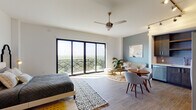 Located at 1320 S Dixie Hwy in Coral Gables, Florida, this single-floor unit offers a thoughtfully designed open-concept layout filled with natural light and contemporary finishes throughout. Wood-look tile flooring runs continuously across the living areas, anchoring the space with warmth and cohesion.

The main living area is expansive and versatile, combining sleeping, lounging, and dining functions seamlessly. A large ceiling fan with brass accents adds character overhead, while floor-to-ceiling sliding glass doors open to a private balcony, framing sweeping, unobstructed views of the lush Coral Gables treetop canopy—a standout feature of this unit.

The kitchen is well-appointed with dark espresso cabinetry, a subway tile backsplash, stainless steel appliances including a French door refrigerator, range, microwave, and dishwasher, complemented by track lighting above.

The sleeping area accommodates a full-sized bed and includes ample closet space, a ceiling fan, and convenient in-unit stacked washer and dryer. A dedicated bathroom features large-format marble-look tile floors, a frameless glass walk-in shower with marble surround, a wood vanity with dual sinks, and a backlit mirror, delivering a refined, spa-like finish.