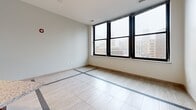This contemporary 560 square foot apartment in Detroit's bustling downtown area showcases a thoughtfully designed single-floor layout. The heart of the home is a modern, open-concept kitchen equipped with rich, dark wood cabinetry and high-end stainless steel appliances. Granite countertops add a touch of luxury, complemented by a stylish pendant light fixture.

The living area seamlessly connects to the kitchen, featuring light wood-look flooring throughout. A standout design element is the unique inlaid tile pattern that creates visual interest and delineates spaces within the open floor plan. Large windows flood the space with natural light and offer impressive views of the surrounding cityscape, enhancing the urban living experience.

The bathroom continues the modern aesthetic with a clean, white color palette, dark wood vanity, and granite countertop matching the kitchen. Light-colored tile flooring maintains consistency with the main living area.

Despite its compact size, the apartment maximizes space efficiency, making it an ideal urban dwelling. The neutral color scheme, contemporary fixtures, and blend of textures create a sophisticated ambiance, perfect for those seeking a stylish city lifestyle in the heart of Detroit.