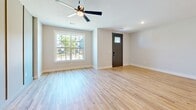 This two-story home in Princeton, TX offers a well-designed layout spread across two floors. The main level features an open-concept kitchen and living area with light hardwood flooring, a ceiling fan, and a large window that fills the space with natural light. The kitchen is a standout, boasting white shaker cabinets, a tiled backsplash, stainless steel appliances, a central island with quartz countertops, a matte black sink, and pendant lighting overhead. A pantry provides additional storage, while the attached garage offers a spacious, functional space with an automatic opener and windowed door panels. Upstairs, the home hosts three carpeted bedrooms, each equipped with ceiling fans and windows overlooking the outdoors. The generously sized primary bedroom includes a walk-in closet outfitted with dual hanging rods and built-in shelving. Two full bathrooms serve the home, featuring clean, neutral finishes with matte black hardware accents including towel rings and toilet paper holders. A hallway connects the upper-level rooms, and five total closets throughout the home ensure ample storage. The consistent use of neutral tones, modern black accents, and quality materials creates a cohesive and contemporary ambiance throughout.