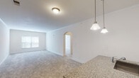 This single-floor residence offers a well-designed open-concept layout that connects the living and kitchen areas seamlessly. The spacious living room features neutral carpet flooring, crown molding, and an elegant arched doorway that adds architectural character. Pendant lighting over the kitchen peninsula creates a warm focal point, while natural light filters in through windows along the exterior wall.

The kitchen is outfitted with rich, dark espresso cabinetry offering generous storage, granite-style countertops, stainless steel appliances including a refrigerator, range, and over-the-range microwave, and a peninsula with a built-in sink — ideal for casual dining or meal prep. Wood-look flooring grounds the kitchen space.

The bedrooms are carpeted and generously sized, each featuring ceiling fans with integrated lighting and windows that bring in natural light. One bedroom includes access to a walk-in closet equipped with wire shelving and hanging rods along multiple walls, providing ample storage.

The bathroom features a soaking tub with subway tile surround and a separate linen closet with built-in shelving, combining both style and practicality. Throughout, the unit maintains a clean, neutral palette that creates a bright and inviting atmosphere.