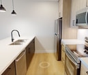Located at 2310 Richmond Street in London, Ontario, this modern 1-bedroom, 1-bathroom apartment offers 710 square feet of thoughtfully designed single-floor living space. Light-toned hardwood flooring runs throughout, creating a cohesive and bright aesthetic across all rooms.

The open-concept living room is a standout feature, boasting large floor-to-ceiling sliding glass doors that lead to a private balcony, flooding the space with natural light and offering expansive views of the surrounding neighbourhood and greenery. Recessed pot lighting complements the natural light throughout.

The kitchen is well-appointed with light wood cabinetry, white quartz countertops, and a navy-accented island featuring a double undermount sink and matte black pendant lighting overhead. Stainless steel appliances including a refrigerator, electric range, and built-in microwave complete the functional and stylish space.

The primary bedroom measures 110 square feet and features a soft blue accent wall, adding a modern design touch. The unit includes two closets for ample storage.

The bathroom is finished with white subway tile surrounding a soaker tub and shower combo, accented by sleek matte black fixtures for a contemporary feel. The unit's clean, neutral palette and modern finishes make it a refined and functional living space.