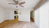 This efficiently designed one-bedroom, one-bathroom unit offers a well-organized single-floor layout. Light wood-tone laminate flooring runs continuously throughout, creating a cohesive and clean aesthetic across all rooms.

The living room serves as the central gathering space, featuring a ceiling fan with integrated lighting and a large sliding glass door dressed with vertical blinds that allows abundant natural light to fill the room. A front entry door with a sidelite window provides additional brightness.

The kitchen is positioned adjacent to the living area and is outfitted with dark wood-grain cabinetry on both upper and lower levels, white quartz countertops, a stainless steel undermount sink, a dishwasher, and a range, offering practical functionality in a compact footprint.

The bedroom is a comfortable, well-proportioned room with its own ceiling fan, a window with blinds for natural light and privacy, and direct access to the main living space.

The bathroom features a full tub-shower combination with white surround walls, a toilet, and a vanity with a white countertop and dark wood-grain cabinetry, finished with a large mirror and overhead lighting. The overall ambiance throughout is bright, clean, and move-in ready.