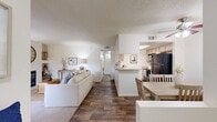 Located in Tucson, Arizona, this single-story, two-bedroom, two-bathroom home offers a thoughtfully arranged floor plan that maximizes functionality within a comfortable footprint. The open-concept main living area seamlessly connects the living room, dining area, and kitchen, creating an inviting, cohesive space ideal for everyday living and entertaining. The living room features neutral tones, a textured ceiling, and built-in shelving, while wood-style flooring runs throughout much of the home, adding warmth and continuity. The dining area includes a ceiling fan and natural light from a window with vertical blinds. The galley-style kitchen is equipped with stainless steel appliances, light wood cabinetry, ample counter space, and a skylight that brightens the workspace. The primary bedroom is generously sized with carpeted flooring, a window view, and access to a walk-in closet. The bathrooms feature wide vanities with ample cabinet storage and shower enclosures with wood-style flooring. A dedicated in-unit laundry room houses a full-size washer and dryer with wire shelving above for additional storage. Throughout the home, a neutral color palette and consistent finishes contribute to a clean, cohesive aesthetic.
