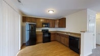 Located at 437 Sunburst Dr in Delaware, Ohio, this two-floor home offers a well-organized layout with functional living spaces throughout. The main living area is generously proportioned, featuring neutral-toned carpet flooring and crisp white walls that create a bright, open atmosphere. Natural light streams in through the windows, illuminating the space and highlighting its clean, move-in-ready condition. A pendant light fixture adds a subtle decorative touch near the dining area, which is conveniently positioned adjacent to the kitchen. The kitchen is a practical and well-appointed space, showcasing rich, warm-toned wood cabinetry that extends from floor to ceiling, providing abundant storage. Granite-look countertops run along the L-shaped layout, complementing the full suite of black appliances, including a refrigerator, electric range with over-the-range microwave, and dishwasher. Light hardwood-style flooring in the kitchen adds warmth and contrast to the darker cabinetry. The home's two-floor design offers separation between living and private spaces, making it suitable for a variety of living arrangements. Overall, the home presents a comfortable and functional environment in a residential neighborhood in Delaware, Ohio.