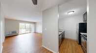 Located at 306 Lexington Pkwy S in Saint Paul, MN, this 2-bedroom, 2-bathroom unit offers a practical and comfortable layout on a single floor. The combined kitchen and living area forms the heart of the space, featuring warm hardwood-style flooring throughout and a ceiling fan with lighting. The kitchen is equipped with dark cabinetry, light countertops, a stainless steel refrigerator, and a dishwasher, neatly separated from the living area by a partial wall. The living room is bright and open, highlighted by a sliding glass door that leads to a private balcony overlooking lush greenery — a standout feature of the space. Baseboard heating runs throughout the common areas and bedrooms, ensuring year-round comfort. Both bedrooms are carpeted and offer a quiet, cozy atmosphere, with the secondary bedroom featuring a window with outdoor views. The primary bedroom is generously sized with its own dedicated closet space. The unit includes two bathrooms: one with a sleek glass-enclosed shower, rich wood vanity, and modern fixtures, and a second with a full soaking tub and shower combination. Four closets throughout the unit provide ample storage. A connecting hallway ties all rooms together in a clean, efficient flow.