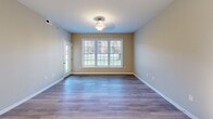Located at 101 YMCA Way in Covington, Virginia, this single-floor residence offers a thoughtfully designed layout with a cohesive, neutral color palette throughout. The space transitions naturally between distinct living areas, each finished with materials suited to their function.

The kitchen is a standout feature, equipped with rich medium-toned wood cabinetry extending to the ceiling for generous storage capacity. Stainless steel appliances—including a full-size refrigerator and microwave—are complemented by a black electric range. White countertops provide a clean contrast, and light wood-look flooring ties the space together. A pendant light fixture and open sightlines to a breakfast bar area add to the kitchen's functionality and visual appeal.

The main living and dining areas feature durable wood-look flooring and large windows that bring in abundant natural light and outdoor views of the surrounding greenery. A decorative ceiling fixture enhances the dining area.

Bedrooms are finished with plush neutral carpeting, and several rooms include ceiling fans with lighting and windows overlooking the exterior. The layout, visible in the 3D overview, reveals a well-organized floor plan connecting living, dining, and private spaces efficiently.

Two bathrooms serve the residence. The full bath includes a tub-shower combination, tile flooring, and a wood-cabinet vanity with a white countertop. A half bath features a matching vanity and tile flooring, providing a practical option for guests.