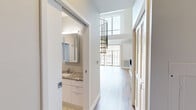 Located in the heart of Detroit at 313 Park Street, this modern two-story residence offers a thoughtfully designed layout spread across two floors. The main level hosts an open-concept kitchen and living area, where warm hardwood floors, soaring ceilings, and floor-to-ceiling windows flood the space with natural light and frame views of the surrounding cityscape. A striking granite-surround fireplace serves as a focal point in the living room, adding both style and warmth. The chef's kitchen is outfitted with sleek flat-front cabinetry, granite countertops, a large center island with an undermount sink, stainless steel appliances including a built-in oven and microwave, and a mosaic tile backsplash. The upper level contains the generously sized primary bedroom, carpeted for comfort, alongside a private outdoor access door leading to a terrace area. Two well-appointed bathrooms feature upscale finishes, including chevron-patterned tile flooring, granite vanity tops with modern white cabinetry, a glass-enclosed walk-in shower, and a soaking tub. Two closets and a hallway complete the layout. Exposed ductwork adds an industrial-chic character throughout this polished urban retreat.