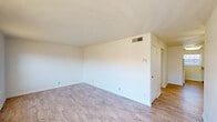 This single-floor, 2-bedroom, 1-bathroom residence offers a thoughtfully arranged layout that maximizes every square foot of its compact footprint. The entry opens into a bright dining area featuring light hardwood-style flooring and a large window fitted with blinds, allowing natural light to fill the space. The adjacent kitchen is well-equipped with warm wood-toned cabinetry, ample counter space, a double-basin stainless steel sink, and a window that brings in additional natural light. White appliances, including a range and dishwasher, complete the functional cooking area. A hallway connects the living areas to the two bedrooms and shared bathroom. The spacious primary bedroom is finished with light hardwood-style flooring, a ceiling fan with integrated lighting, and a HVAC vent for year-round comfort. The second bedroom features plush carpeting, a window with natural light, and its own HVAC vent. Both bedrooms offer clean white walls and a neutral palette ideal for personalization. The full bathroom includes a tiled tub-shower combination with chrome fixtures and classic tile wainscoting, maintaining a clean and functional aesthetic throughout. A dedicated closet provides additional storage within this efficiently organized home.