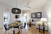 Located in Atlanta's vibrant Grant Park neighborhood, this thoughtfully designed 2-bedroom, 2-bathroom residence offers a seamless single-floor layout with contemporary finishes throughout. The open-concept living area combines the kitchen, dining, and living spaces into one cohesive, light-filled environment with light wood-tone flooring and high ceilings that enhance the sense of openness.

The kitchen is a standout feature, showcasing dark wood-grain cabinetry, quartz countertops, stainless steel appliances, a subway tile backsplash, and a generous island with seating — illuminated by a trio of modern pendant lights. A dedicated pantry adds convenient storage. The dining area flows effortlessly into the living room, which opens to a private balcony through floor-to-ceiling glass doors.

The primary bedroom is a spacious retreat with large windows, a dramatic accent wall, and ample closet space. The secondary bedroom is equally well-proportioned with natural light and closet access. Both bathrooms are finished with clean tile work, modern fixtures, and warm wood vanities. Additional conveniences include a dedicated laundry area and utility room, completing this well-appointed residence.