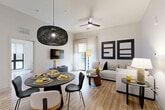 Located in Atlanta's vibrant Grant Park neighborhood, this thoughtfully designed 2-bedroom, 2-bathroom residence offers a seamless single-floor layout with contemporary finishes throughout. The open-concept living area combines the kitchen, dining, and living spaces into one cohesive, light-filled environment with light wood-tone flooring and high ceilings that enhance the sense of openness.

The kitchen is a standout feature, showcasing dark wood-grain cabinetry, quartz countertops, stainless steel appliances, a subway tile backsplash, and a generous island with seating — illuminated by a trio of modern pendant lights. A dedicated pantry adds convenient storage. The dining area flows effortlessly into the living room, which opens to a private balcony through floor-to-ceiling glass doors.

The primary bedroom is a spacious retreat with large windows, a dramatic accent wall, and ample closet space. The secondary bedroom is equally well-proportioned with natural light and closet access. Both bathrooms are finished with clean tile work, modern fixtures, and warm wood vanities. Additional conveniences include a dedicated laundry area and utility room, completing this well-appointed residence.