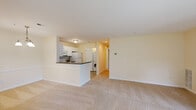 Located at 9015 Thamesmeade Rd in Laurel, Maryland, this single-floor residence offers a well-organized, open-concept layout designed for comfortable everyday living. The spacious living area is finished with plush wall-to-wall carpeting and painted in soft, neutral tones that lend a bright and airy feel throughout. Large sliding glass doors flood the living room with natural light while providing direct views of the surrounding greenery, complemented by a secondary window near the front entry. A bold teal front door adds a distinctive accent to the otherwise understated palette.

The kitchen is positioned along one side of the open living space, defined by a breakfast bar peninsula with a dark granite-style countertop. White cabinetry extends to the ceiling, offering generous storage, while white appliances — including a refrigerator, electric range, built-in microwave, and sink — provide a clean, cohesive look. Tile flooring grounds the kitchen area, transitioning seamlessly to the laundry nook, which features a stacked washer and dryer unit.

The bedrooms are carpeted and generously sized, each benefiting from natural light through well-placed windows. Closet space is provided via full-width bi-fold doors. The bathroom is finished with tile flooring, a white vanity with mirror, and a full soaking tub with shower surround, maintaining the home's consistent neutral aesthetic.