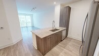 Located at 360 Village Drive in King of Prussia, PA, this one-bedroom, one-bathroom residence offers a thoughtfully designed open-concept layout. Light wood-style flooring runs throughout the main living areas, complementing the clean, neutral palette of crisp white walls and bright recessed lighting.

The kitchen is a standout feature, showcasing rich dark wood cabinetry that extends to the ceiling for ample storage, granite countertops with subtle variation, a central island with an undermount sink, and a full suite of stainless steel appliances including a range, microwave, and French door refrigerator. The kitchen flows seamlessly into the living area, creating a connected, functional space ideal for everyday living and entertaining.

The bedroom is a comfortable, well-proportioned retreat featuring light hardwood-style flooring, soft neutral walls, and a large window fitted with horizontal blinds that allows natural light to fill the room while providing views of the surrounding community.

The bathroom is finished with polished large-format tile flooring, a sleek dark wood vanity with granite countertop, an undermount sink, and a well-lit mirror. Additional doors visible from the hallway suggest convenient closet access nearby. The overall ambiance of the residence is modern, clean, and move-in ready.