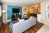 This single-floor residence at 3801 Oak Valley Dr in Knoxville, Tennessee offers a well-organized and cohesive living environment with a welcoming aesthetic throughout. The open-concept living and dining area seamlessly connects the two spaces, featuring rich hardwood-style flooring, a ceiling fan, and a vibrant teal accent wall that adds a pop of color. Natural light filters in through windows dressed with stylish two-tone drapes, enhancing the warm and inviting ambiance. The kitchen is well-appointed with warm oak cabinetry, granite-style countertops, tile flooring, a full suite of appliances including a dishwasher, electric range, and refrigerator, providing ample storage and prep space. The dining area, adjacent to the kitchen, is accented by tasteful artwork and flows naturally into the living space. The two bedrooms each feature plush carpeting, ceiling fans, and accent walls in calming hues, with windows that allow for natural light. The bathrooms are cleanly finished with tile flooring and a tub-shower combination. A dedicated in-unit laundry area adds everyday convenience. Overall, the space presents a comfortable and functional layout ideal for modern living.
