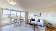 Located at 10 De Sabla Rd in San Mateo, CA, this single-floor residence offers a comfortable and well-organized layout bathed in natural light. The open-plan living and dining area is a standout feature, anchored by warm hardwood flooring and large floor-to-ceiling windows that frame sweeping panoramic views of the surrounding San Mateo treetops and skyline. The living space provides ample room for relaxing and entertaining, with a welcoming, airy ambiance throughout.

The dining area sits directly beside the expansive windows, making it an especially bright and scenic spot for everyday meals. The kitchen is efficiently designed with light wood cabinetry, granite-style countertops, and full appliance suite including an electric range, dishwasher, and refrigerator — all set over continuous hardwood flooring.

The bedroom is a peaceful retreat, featuring the same warm hardwood floors, a bright window with garden and neighborhood views, and a dedicated desk area — ideal for working from home. A built-in closet and entry foyer with additional storage complete the layout.

The bathroom features classic yellow tile detailing with a full tub-shower combination, a pedestal sink, and chrome fixtures, lending a timeless mid-century character to the space.