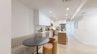 Located in the desirable Beverly Grove neighborhood of Los Angeles, this thoughtfully designed single-floor residence offers five bedrooms and three bathrooms with a clean, contemporary aesthetic. The open-concept living area seamlessly integrates the kitchen, dining, and living spaces into one bright, cohesive layout. The kitchen is outfitted with high-gloss white cabinetry, stainless steel appliances, a subway tile backsplash, and a wood-paneled island with bar seating — ideal for both cooking and casual dining. Light wood-style flooring runs throughout, contributing to a warm yet modern atmosphere. Each of the five bedrooms features large windows that invite generous natural light and provide views of the surrounding Los Angeles cityscape, along with individual closets for ample storage. The bedrooms maintain a minimalist design with clean white walls and dedicated mini-split climate control systems. All three bathrooms are finished with floor-to-ceiling white tile, geometric-patterned tile flooring, glass-enclosed walk-in showers, and sleek modern fixtures. Built-in shelving in select bathrooms adds practical storage. Two hallways connect the well-organized layout efficiently, making this a highly functional and stylish home in a prime Los Angeles location.