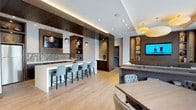 Located at 4901 Montgomery Lane in the heart of Bethesda, Maryland, Unit 205 is a thoughtfully designed residence that combines modern aesthetics with functional living. The open-concept main living area seamlessly connects the kitchen, dining, and living spaces, creating a bright and cohesive environment. Dark hardwood flooring runs throughout, grounding the space with warmth and sophistication.

The contemporary kitchen is outfitted with light wood cabinetry, a crisp white quartz countertop, a subway tile backsplash with under-cabinet lighting, and a full suite of stainless steel appliances. A central island with seating provides both additional prep space and a natural gathering spot for casual dining.

The living area features floor-to-ceiling windows and a glass sliding door that opens onto a private balcony, flooding the room with natural light and offering pleasant outdoor views of the surrounding Bethesda neighborhood.

The bedroom is a serene retreat, featuring large windows with roller shades, dark hardwood floors, and a calm, neutral palette. The bathroom is finished with tile flooring, a soaking tub with shower, and a wood-framed vanity mirror with quartz countertops.

Residents also enjoy access to a spacious shared outdoor terrace with modern lounge seating and dining areas, ideal for relaxing or entertaining outdoors.
