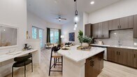 Located at 14440 Pearson Market Cir in Austin, TX, this thoughtfully designed one-bedroom, one-bathroom residence offers a modern open-concept layout with high ceilings and light-toned hardwood-style flooring throughout. The kitchen is a standout feature, showcasing rich dark wood cabinetry, a classic subway tile backsplash, stainless steel appliances, and a spacious island with a striking quartz countertop accented by elegant veining. Globe pendant lights hang above the island, adding a contemporary touch. The kitchen flows seamlessly into the living area, which is bathed in natural light from large windows dressed with stylish drapery and a ceiling fan overhead. The bedroom is a serene retreat featuring a window with outdoor views, a barn-style door detail, and access to a dedicated walk-in closet outfitted with multi-level shelving and hanging rods for ample storage. The bathroom is clean and refined, featuring a dark wood vanity with an undermount sink, a full-width mirror, and a glass-enclosed walk-in shower with large-format tile surround. Built-in shelving near the bathroom entry adds practical storage. The overall ambiance is modern and welcoming, with a cohesive neutral palette throughout.