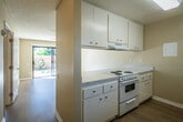 Located at 1939 Wallace Ave in Costa Mesa, CA, this single-story, one-bedroom, one-bathroom home offers a well-organized and efficiently designed layout. The galley-style kitchen is outfitted with white cabinetry, speckled countertops, a white electric range, and a double-basin stainless steel sink, all set atop light wood-style flooring. A window in the kitchen brings in natural light and a view of the surrounding area. The kitchen opens directly to the living room, which features sliding glass doors leading to a private, fenced patio — a sun-drenched outdoor space with tropical plantings that evokes the relaxed Southern California lifestyle.

The generously sized bedroom is carpeted and bathed in natural light from a window, with a ceiling fan providing comfort year-round. Textured ceilings are consistent throughout the home. The bedroom connects to a dedicated walk-in closet, offering ample storage with wrap-around shelving and hanging rods. The bathroom is clean and functional, featuring light tile flooring, a shower/tub combination, and standard fixtures. The entire home is finished in neutral, warm tones, creating a cohesive and inviting atmosphere suited for comfortable everyday living.