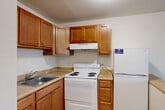 Located at 2206 N Berkshire Rd in Charlottesville, VA, this single-floor, two-bedroom unit offers a practical and well-organized layout. The combined kitchen and living area forms the heart of the home, with the kitchen featuring warm wood-toned cabinetry, a coil electric range, a full-size refrigerator, a stainless steel sink, and a peninsula counter that opens toward the living space — ideal for both cooking and casual dining. Wood-style laminate flooring runs consistently throughout the unit, lending a cohesive and clean aesthetic.

The living area benefits from a large window that admits natural light and offers views of surrounding greenery. Both bedrooms are well-proportioned, with the primary bedroom providing a generous amount of space, a double-door closet, and a window with outdoor views. The secondary bedroom also features a window with natural light and baseboard heating. Neutral wall tones throughout create a calm, move-in-ready environment.

A dedicated laundry area houses the unit's water heater and utility connections. Wall-unit air conditioning is present in the living area, complementing the baseboard heating found in the bedrooms. The layout is efficient and functional, making effective use of every room for comfortable day-to-day living.