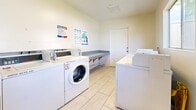 Located at 301–307 Avocado St in Costa Mesa, California, this shared laundry facility offers a clean, functional, and efficiently organized space designed to serve the needs of its users. The room features light-toned walls and light tile flooring throughout, contributing to a bright and tidy atmosphere.

The facility is equipped with multiple commercial-grade front-load and top-load washing machines, as well as several Speed Queen commercial dryers — all from the WASH laundry service network — providing ample capacity for simultaneous use. A built-in folding counter runs along one wall, offering a convenient surface for sorting and folding laundry. Informational signage, including laundry room guidelines and mobile payment instructions, is posted on the walls for easy reference.

Natural light filters into the space through a window, adding to the overall brightness of the room. A dedicated electrical panel is also visible, reflecting the room's practical infrastructure. The single-story layout is compact yet well-utilized, ensuring ease of movement between the machines and the folding area. The space is accessed through a standard door and maintains a straightforward, no-frills design focused entirely on functionality and convenience for residents.
