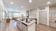 This well-appointed 2-bedroom, 2-bathroom residence in Lakeland, Florida offers a thoughtfully designed single-floor layout with a clean, modern aesthetic throughout. The open-concept living and kitchen area serves as the heart of the home, featuring light wood-style flooring, recessed lighting, and a seamless flow between spaces. The kitchen is outfitted with white shaker cabinetry, granite countertops with a tile backsplash, and a full suite of stainless steel appliances including a refrigerator, range, microwave, and dishwasher. A peninsula counter provides additional prep space and casual dining potential.

The primary bedroom is a comfortable retreat complete with plush carpet, a ceiling fan, and direct access to a dedicated bathroom and walk-in closet with built-in shelving. The primary bathroom impresses with a double-sink vanity topped with granite, matte black fixtures, and a glass-enclosed walk-in shower. The second bedroom mirrors the same carpeted comfort and ceiling fan, with its own closet and adjacent bathroom featuring a soaking tub.

A standout feature is the sun-drenched corner nook lined with expansive windows offering sweeping outdoor views of the surrounding Lakeland community, filling the space with abundant natural light.