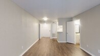 Located at 6425 Bankside Dr in Houston, TX, this two-story, one-bedroom, two-bathroom home offers a practical and well-organized layout across two floors. The main level features a spacious living area finished with warm hardwood-style flooring and soft neutral walls, creating a clean and inviting atmosphere. A kitchen with a pass-through counter is conveniently accessible from the living space, alongside a full bathroom fitted with a tub-shower combination and wood-style flooring. A carpeted staircase with white baluster railings connects the two floors. The upper level hosts the generously sized primary bedroom, carpeted for comfort, and filled with natural light through a large sliding glass door dressed with vertical blinds that offer views of the surrounding greenery. The bedroom includes a dedicated walk-in closet with built-in shelving and is adjacent to a second full bathroom featuring a marble-topped vanity with white cabinetry. Throughout the home, the consistent use of neutral tones, clean white trim, and updated finishes contributes to a cohesive and move-in-ready aesthetic. The two-story design provides a clear separation between living and sleeping areas, making efficient use of the available space.